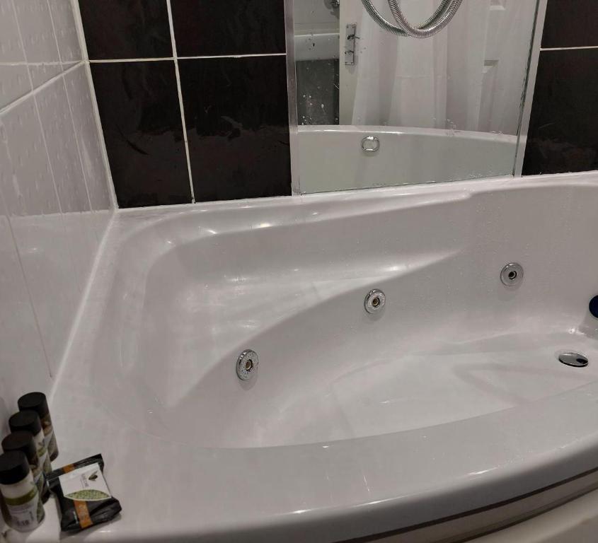 a white bath tub sitting in a bathroom at Three Bed House with free on-site parking Sleeps 5 in Warrington