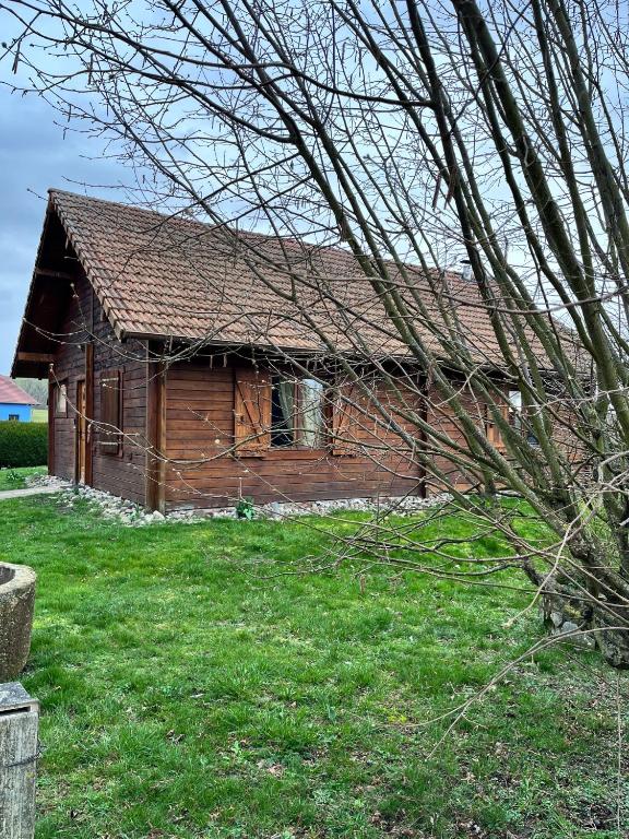 une ancienne cabane en rondins dans un champ d'herbe verte dans l'établissement L’atelier des rêves, à Volmunster