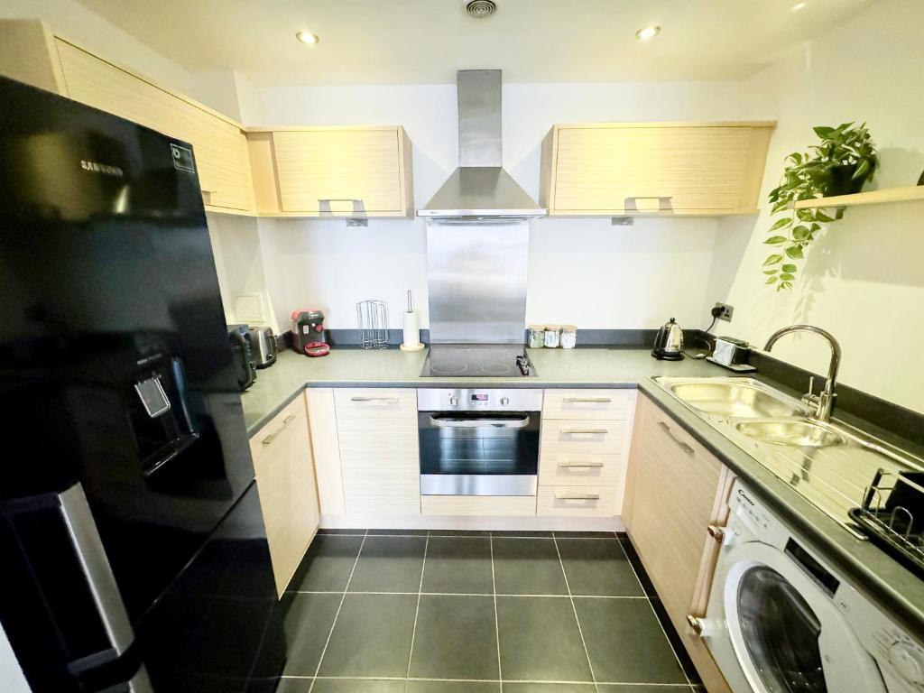 uma cozinha com armários brancos e um frigorífico preto em Stylish + Peaceful 2 bed/2bath em Slades Green