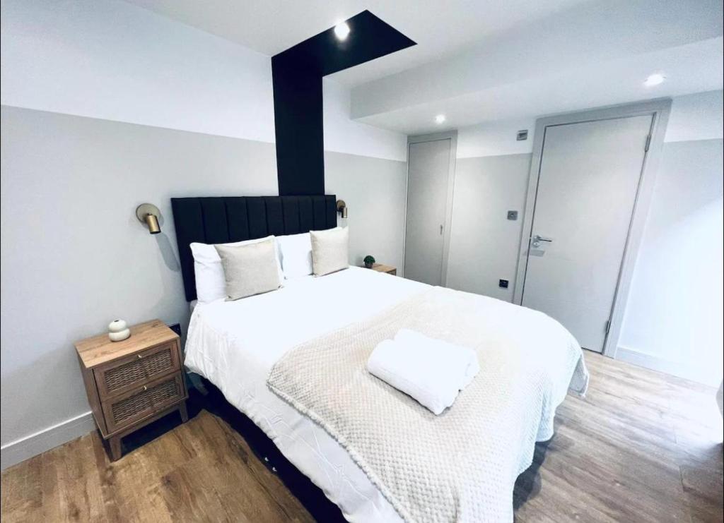 a bedroom with a large white bed and a wooden floor at Charming En-Suite in London in London