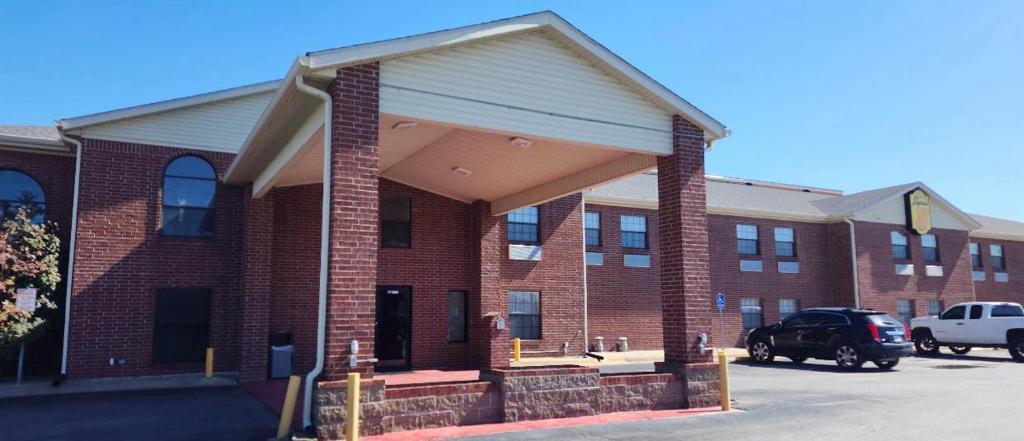 a brick building with a car parked in a parking lot at Super 8 by Wyndham White Hall in White Hall