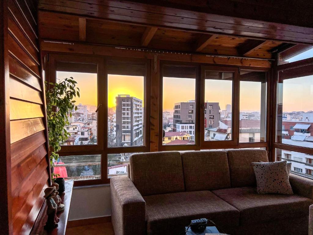 a living room with a couch in front of a window at SkyView Oasis Premium Apartment in Tirana