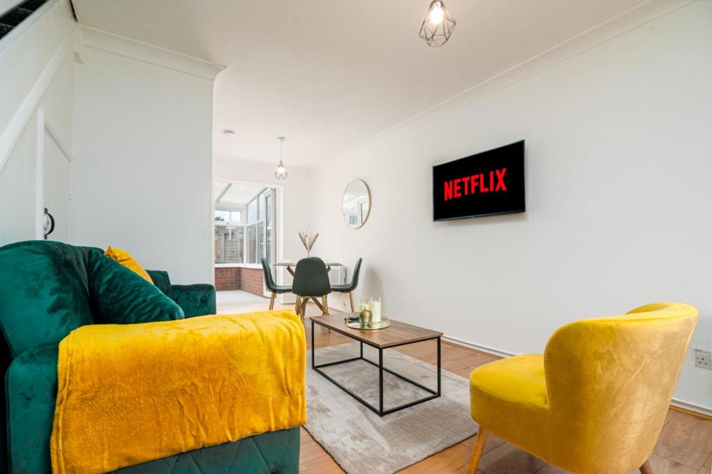 a living room with a green couch and a yellow chair at Luxurious 2 bed house - Free Parking in Thamesmead