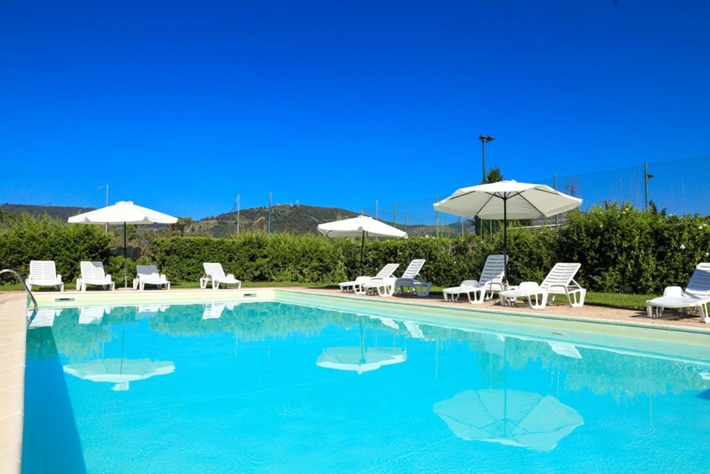 een zwembad met stoelen en parasols bij Garden Hotel Alghero in Fertilia