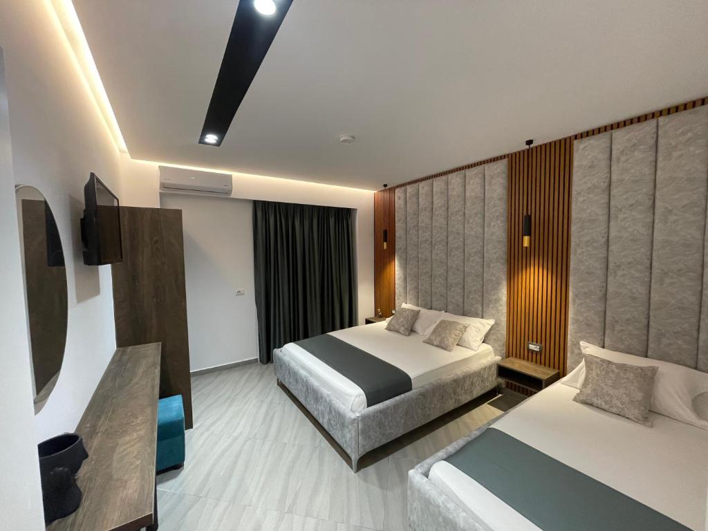 een hotelkamer met 2 bedden en een televisie bij Julies Vila in Ksamil