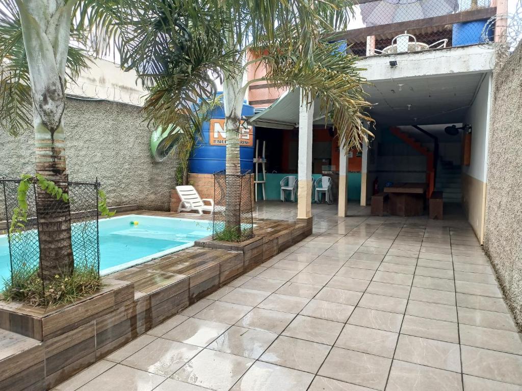 a swimming pool with palm trees next to a building at Espaço com piscina in Sorocaba