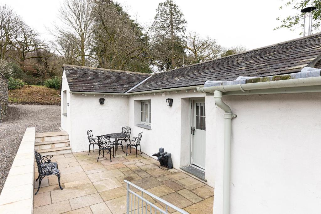 a white house with a patio with chairs and a table at The Bothy in Ulverston