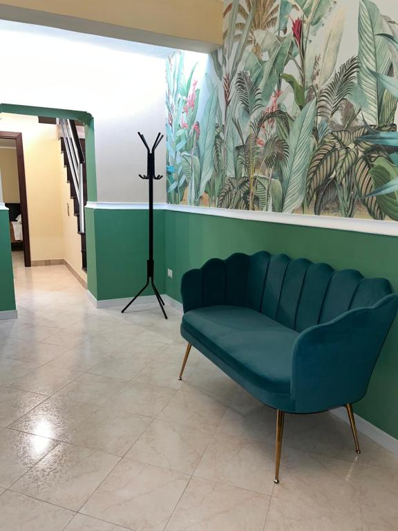 un sofá azul en una habitación con una pared verde en Piazzetta 42 Holiday Room, en Trani