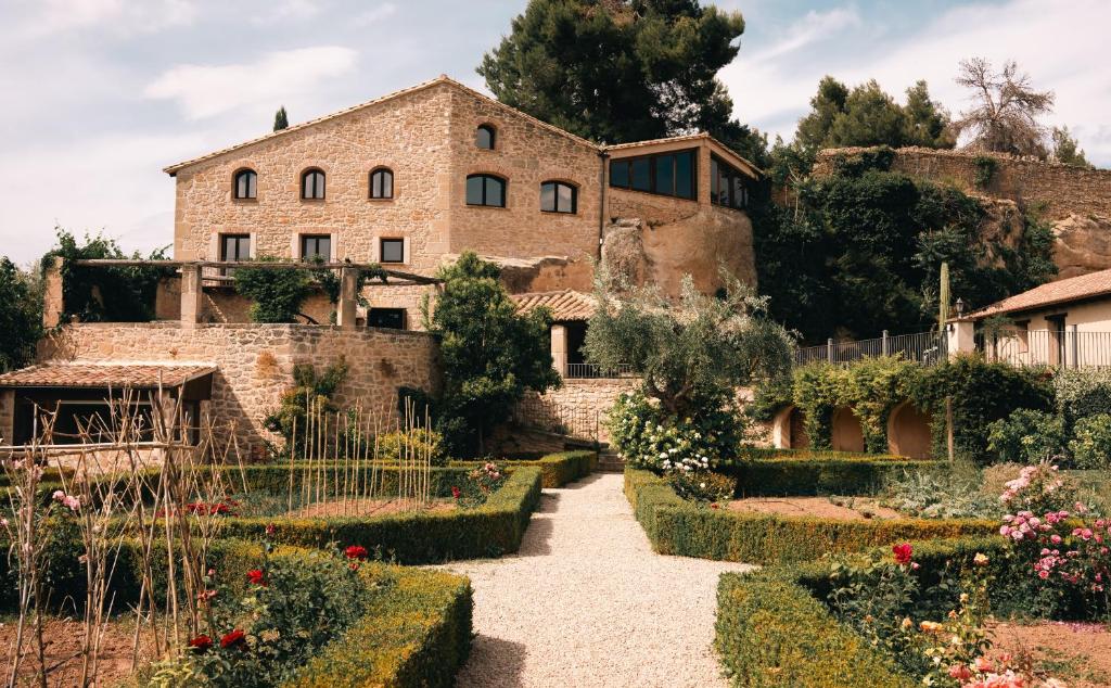 une ancienne maison en pierre avec un jardin en face de celle-ci dans l'établissement Hotel Hort De Fortunyo, à Arnés