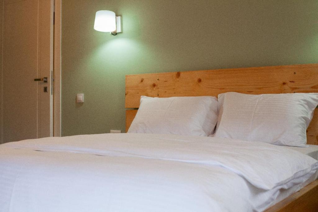 uma cama com lençóis brancos e almofadas num quarto em Vila Nikol em Voskopojë