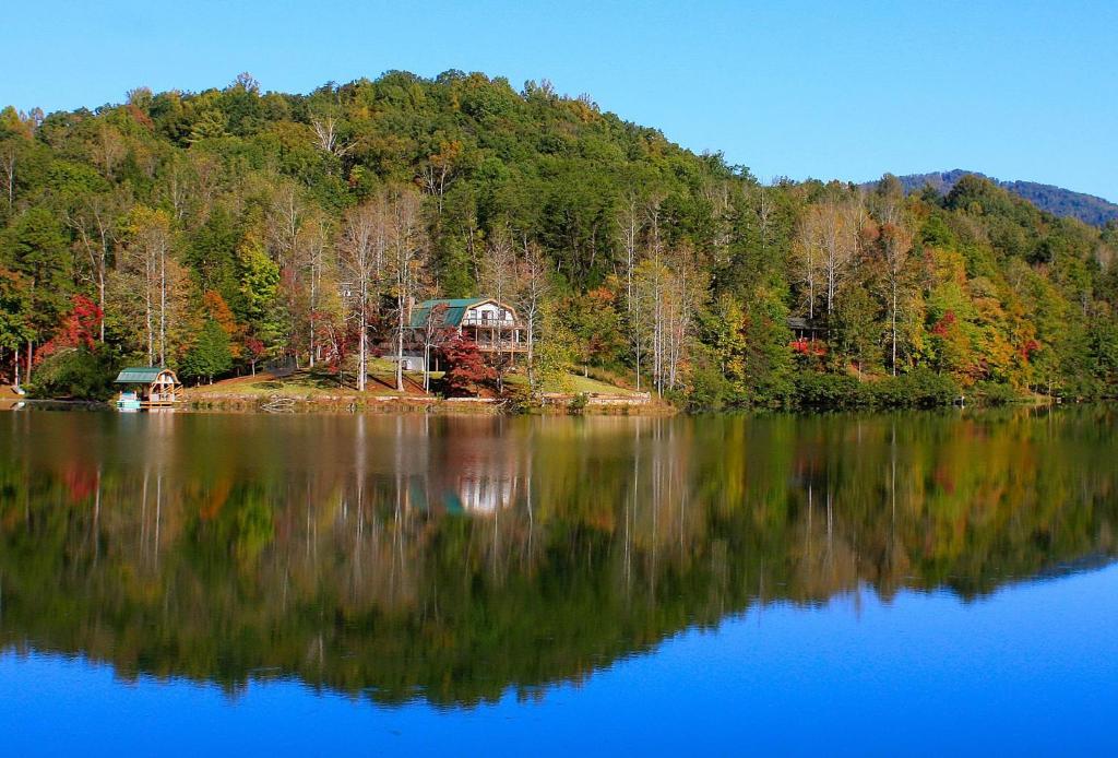 un reflet d'une maison dans un lac avec des arbres dans l'établissement Lake Lure Retreat - A Beautiful Lakefront Lodge on Mirror Lake-Waterfront-Newly Expanded Deck lodge, à Lake Lure