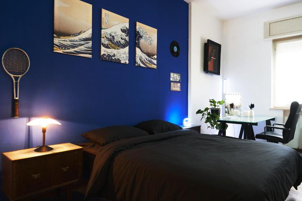 um quarto com uma parede azul com uma cama e uma mesa em Blue Note Apartment em Montesilvano