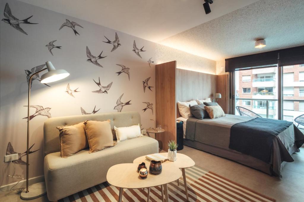 - une chambre avec un lit, un canapé et des oiseaux sur le mur dans l'établissement Exclusivo apartamento en Punta Carretas, à Montevideo