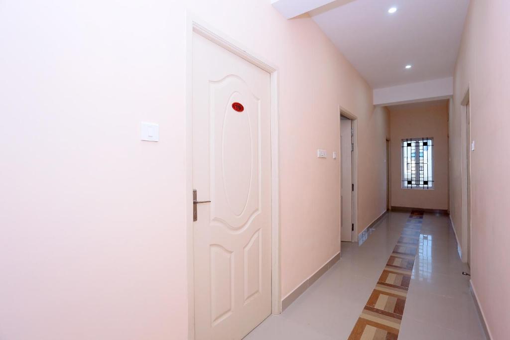 un pasillo con paredes blancas y una puerta en OYO Flagship Viswa Towers, en Madurai