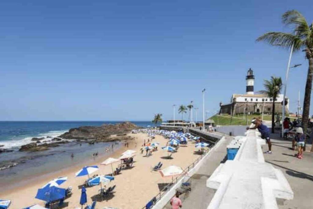a beach with a lot of people and a lighthouse at Vem curtir na praia e na cidade. in Salvador