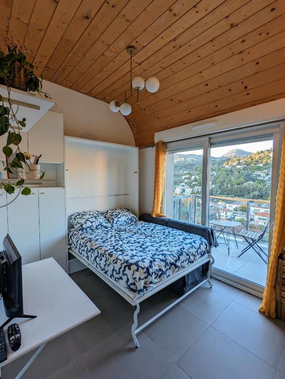 une chambre avec un lit et une grande fenêtre dans l'établissement Studio calme avec vue dégagée, à Nice