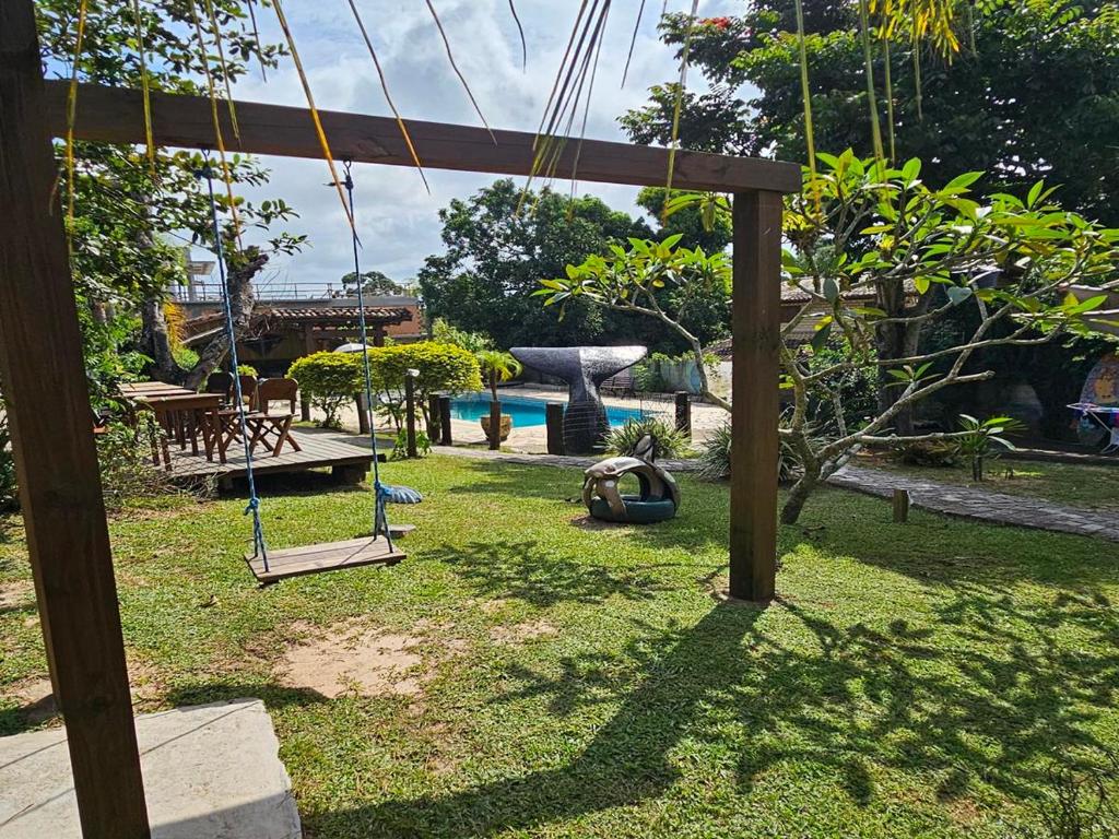 un parque infantil con un columpio en un patio en Pousada Meia Lua, en Praia do Rosa