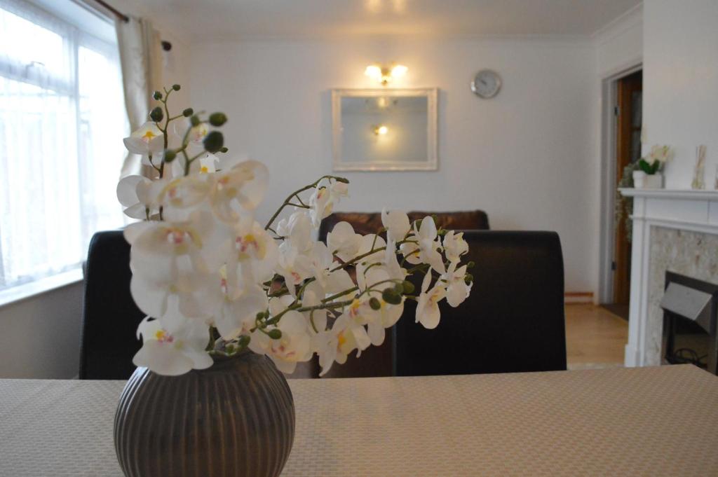 a vase filled with white flowers sitting on a table at Luton Lodge - Near London Luton Airport Luxury Quite Rooms Close to Restaurants & Shops in Luton