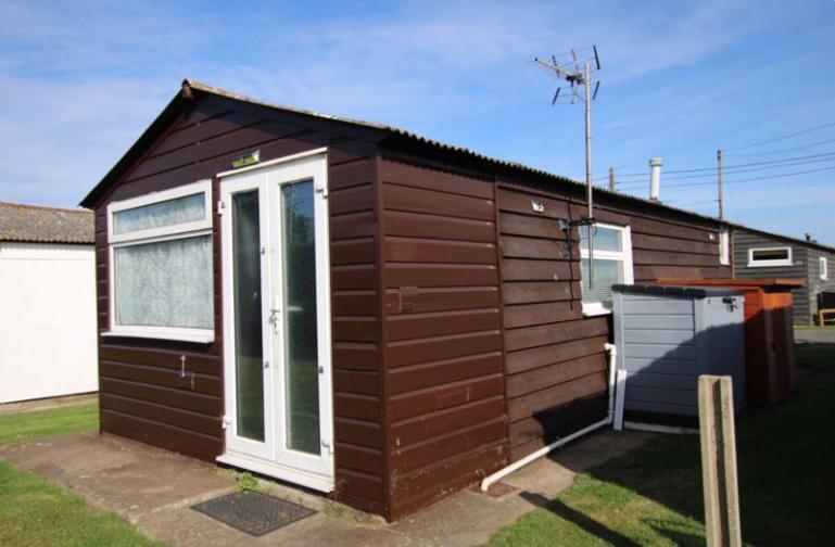 a small cabin with a door in a yard at Beautiful Chalet close to the beach in Eastchurch