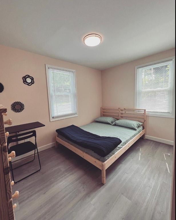 a bedroom with a bed and a desk and two windows at Guest House Baltimore County in Parkville