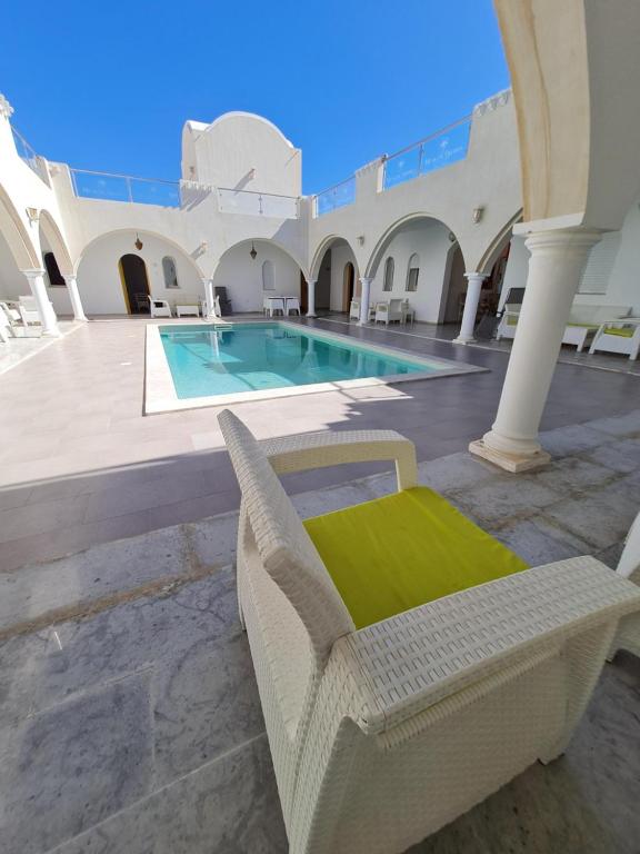 a pool in a building with a chair and a swimming pool at Musk de djerba suite aziz avec piscine in Temlale