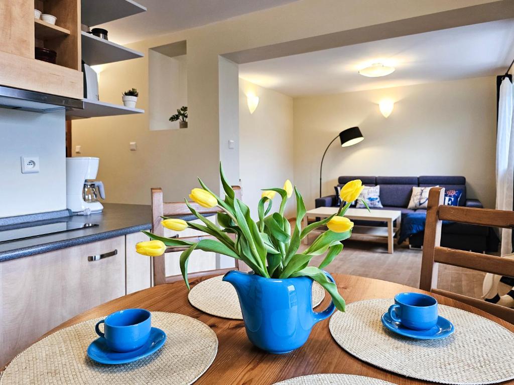 kuchnia i salon ze stołem z dwoma talerzami i niebieską wazą w obiekcie visit baltic - Przy Promenadzie Apartament Kapitański w Świnoujściu