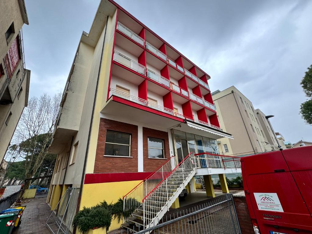 un edificio rosso e giallo con una scala sopra di Hotel Serafini a Rimini