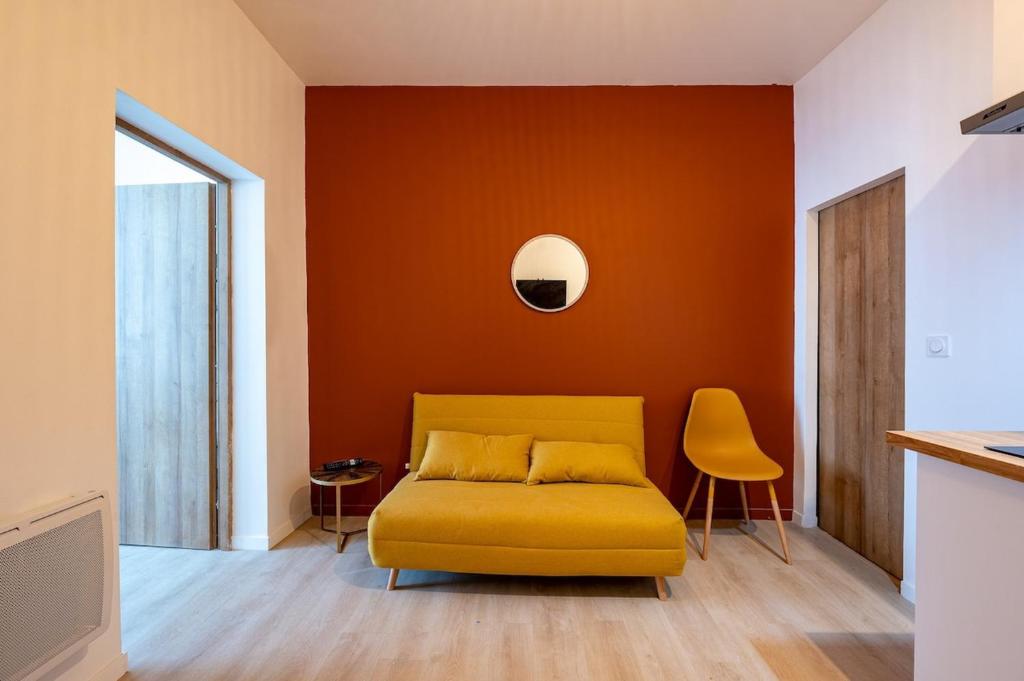 un sofá amarillo en una habitación con una pared naranja en Les Maisons Acajou - Valenciennes, en Valenciennes