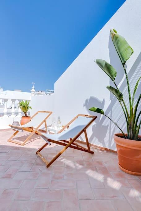 a patio with two chairs and a potted plant at Casa da Trindade Olhão - Boutique Collection in Olhão