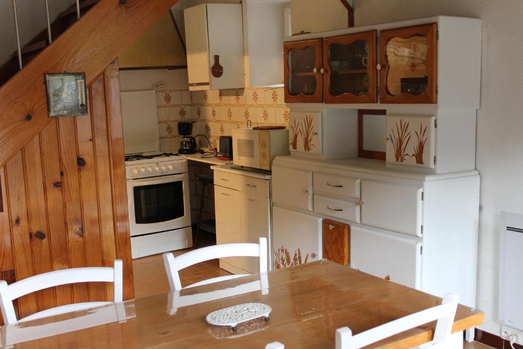 een keuken met een tafel en witte apparaten bij MAISON AUGUY in Saint-Julien-Boutières