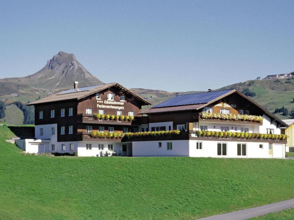 a house in a field with a mountain in the background at Modern apartment with swimming pool in Damüls in Damuls