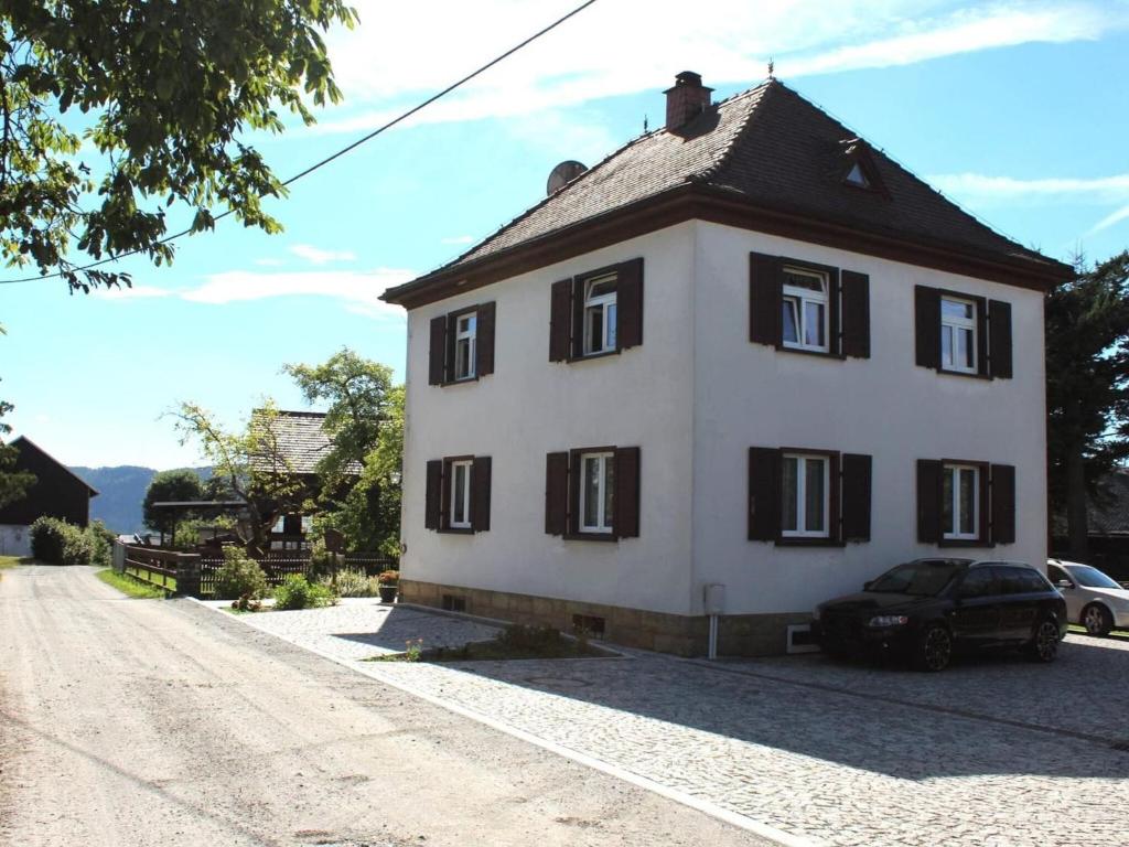 a white house with black windows on a dirt road at Holiday apartment in the Saxon Switzerland National Park in Lichtenhain