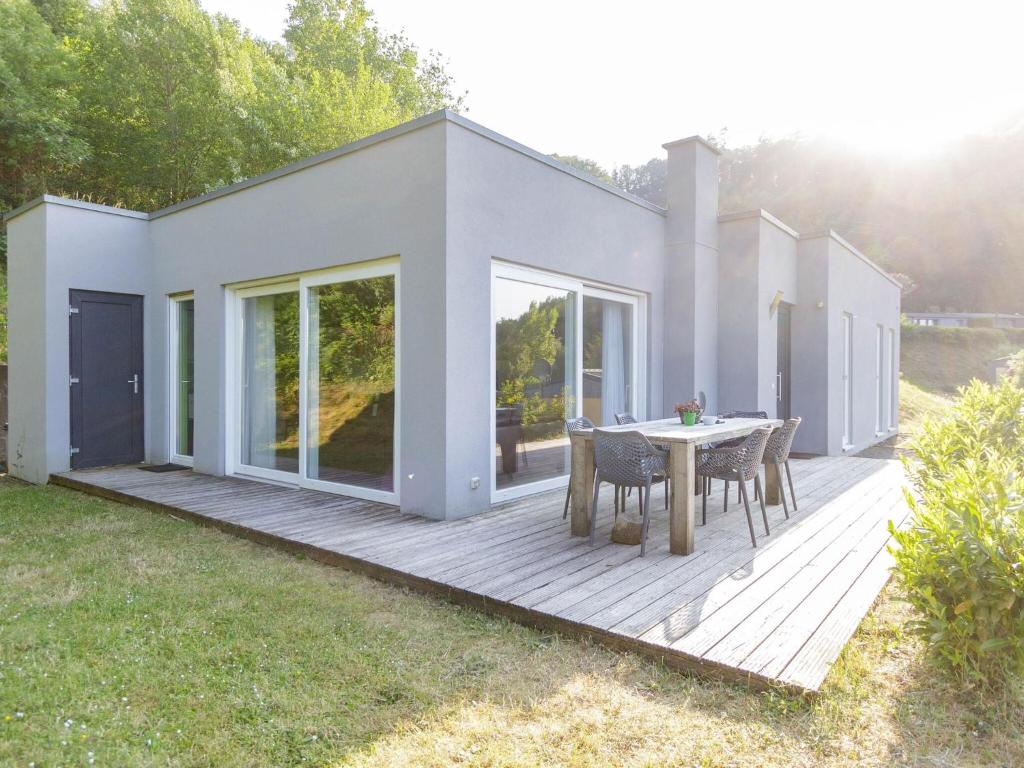 a house with a wooden deck with a table at Luxurious bungalow in Waxweiler in the Eifel in Waxweiler