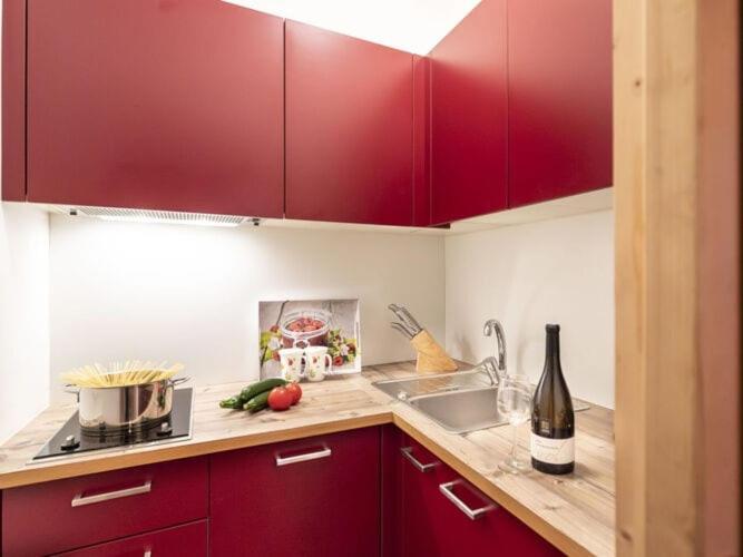 una cocina con armarios rojos y una botella de vino en Nice apartment in Meran, en Merano