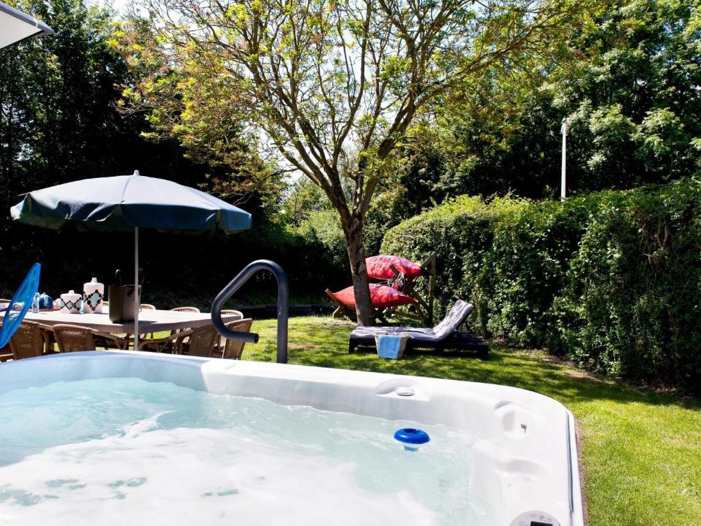 wanna na dziedzińcu ze stołem i parasolem w obiekcie Luxury home with sauna and outdoor spa w mieście Earnewâld