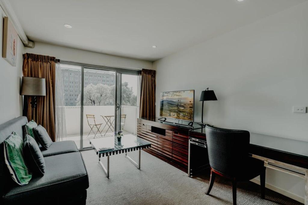 een woonkamer met een bank en een tafel bij Urban 1-Bed Apartment in the Heart of the City in Canberra