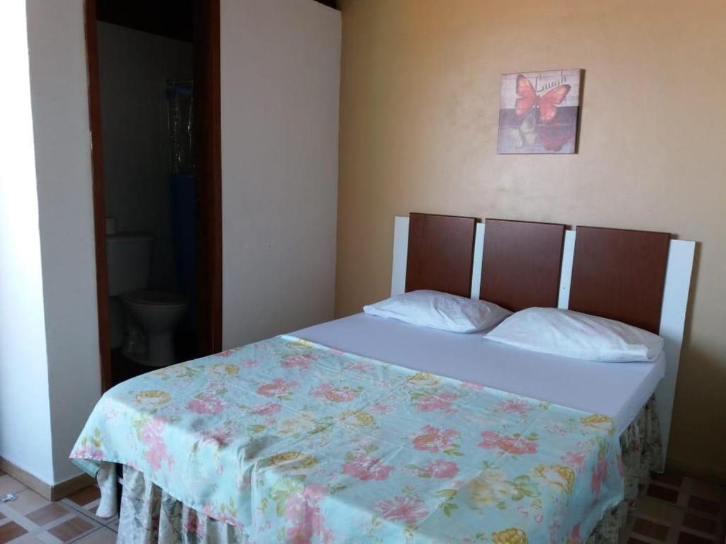 um quarto com uma cama com uma colcha florida em Pousada Cantinho da Nilza em Cabo Frio