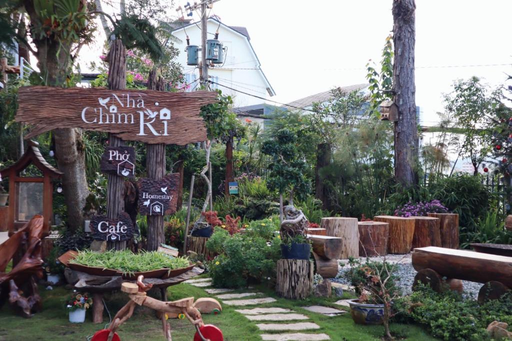 un jardín con un cartel en la hierba en Nhà Chim Ri - Homestay Cafe Đà Lạt, en Da Lat