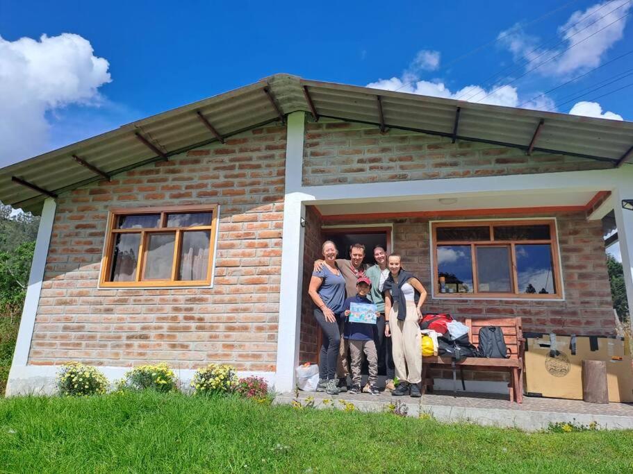 Un gruppo di persone che si trovano di fronte a una casa di Cozy cabin in the countryside Otavalo Learning a Otavalo