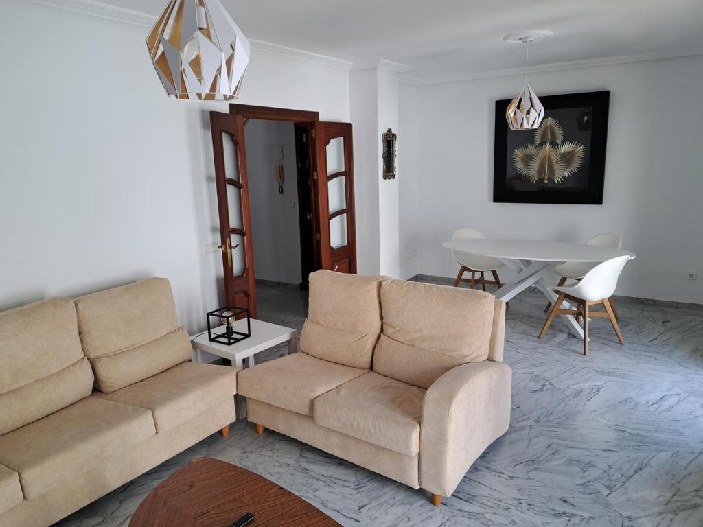 a living room with two couches and a table at Encanto Urbano: Piso céntrico totalmente equipado in Lebrija