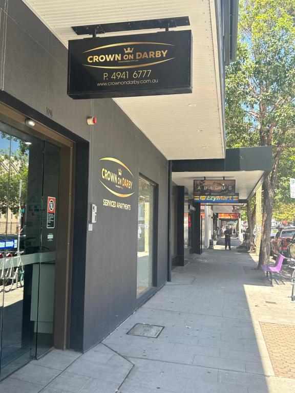 a building with a sign for a store on a sidewalk at Crown on Darby Newcastle in Newcastle