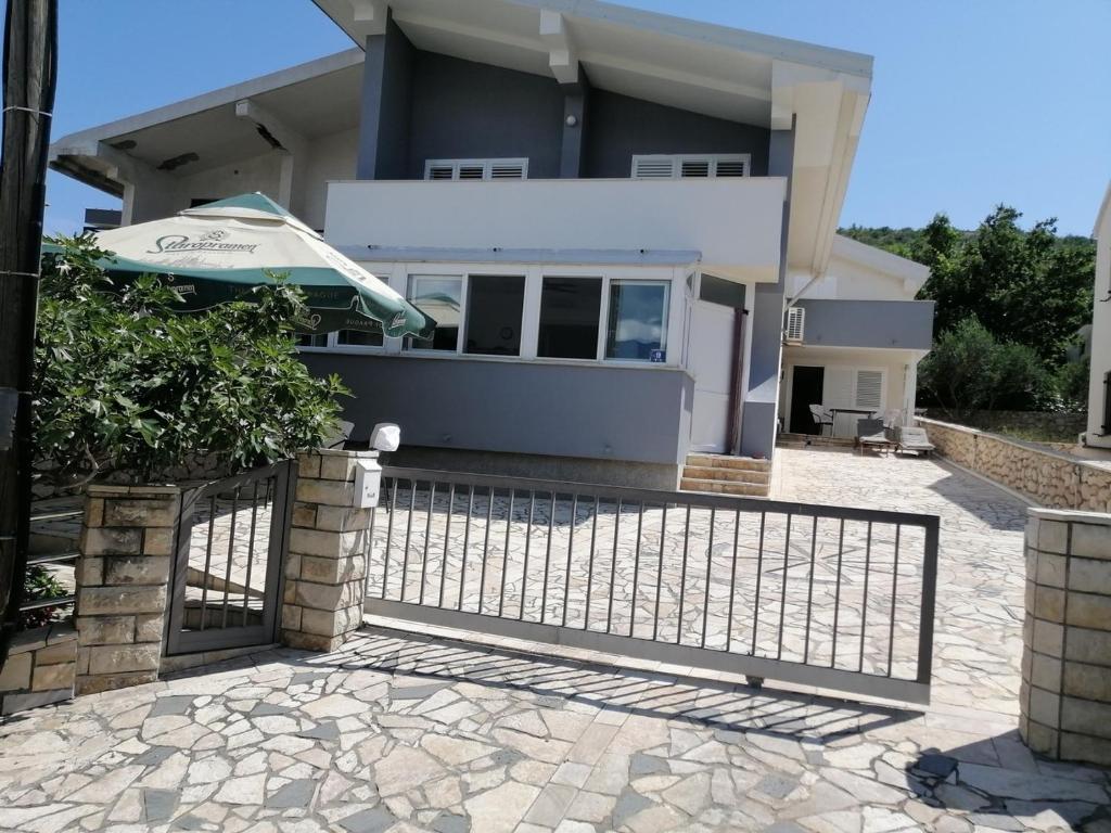 a house with a fence and an umbrella at Apartments with a parking space Vinjerac, Zadar - 22585 in Posedarje