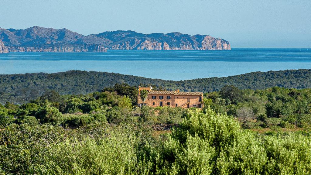 a house on a hill with the water and mountains at Sos Ferres D'en Morey in Manacor
