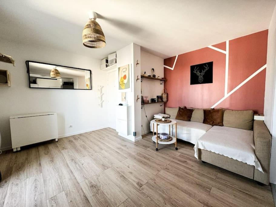 - un salon avec un canapé blanc et un mur rose dans l'établissement Un nid douillet pour les JO, à Saint-Denis