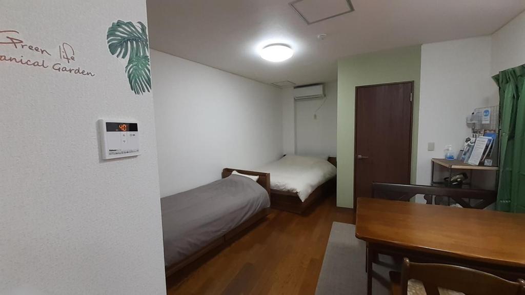 Habitación pequeña con cama, escritorio y mesa. en Noah House 102貸切, en Shingu