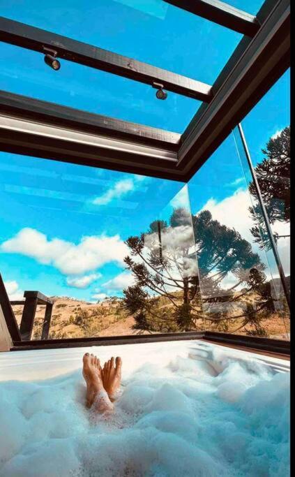 a person laying in a bath tub with their feet in it at Winter Valley Cabins in São Joaquim