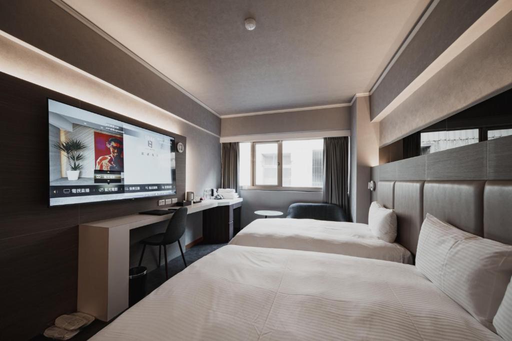 um quarto de hotel com duas camas e uma televisão de ecrã plano em Hub Hotel Kaohsiung Yisin Branch em Kaohsiung