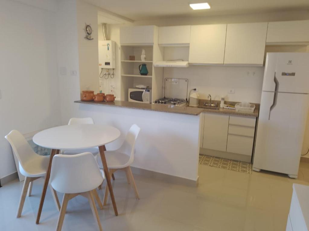 a kitchen with a table and chairs and a refrigerator at Praia Mansa Caiobá 3 quartos in Matinhos