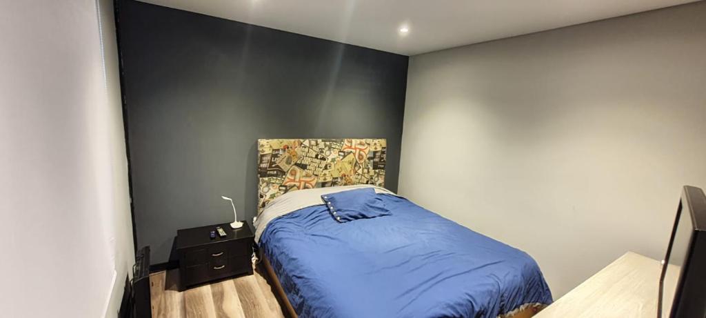 - une chambre avec un lit bleu et un mur dans l'établissement Apartaestudio en Chía, à Chía