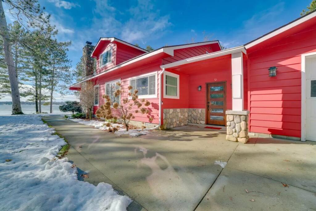 una casa roja con entrada en la nieve en Redwood Retreat by the Lake, en Oscoda